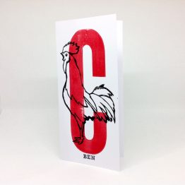 Carte postale artisanale représentant un coq et la lettre C en rouge.